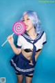 A woman in a sailor outfit holding a lollipop.