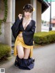 A woman in a black and yellow kimono posing for a picture.