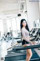 A woman standing on a treadmill in a gym.