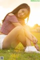 A woman sitting on the grass with her legs crossed.