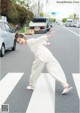 A woman in a white jumpsuit is crossing the street.