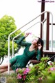 A woman in a green dress sitting on a bench.