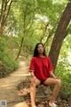 A woman in a red shirt is sitting on a stone bench.