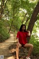 A woman in a red shirt is sitting on a stone bench.