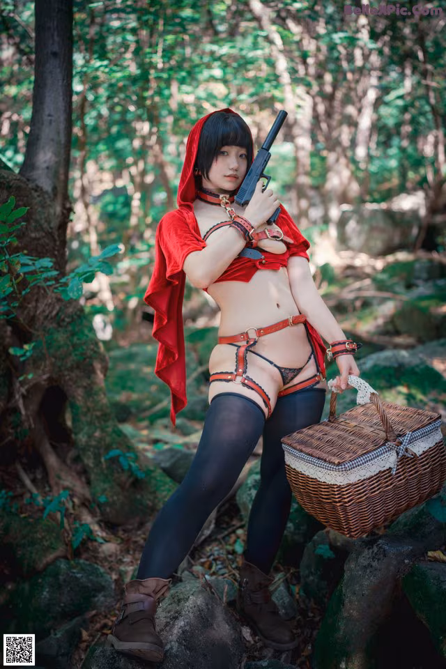 A woman dressed as a red riding hood holding a gun and a basket.