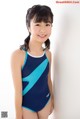 A young girl in a blue and black swimsuit posing for a picture.