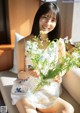 A woman sitting on a couch holding a vase of flowers.