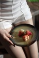 A woman holding a plate with strawberries on it.