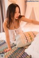 A woman laying on top of a bed next to pillows.