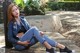 A woman sitting on a wooden bench in a park.